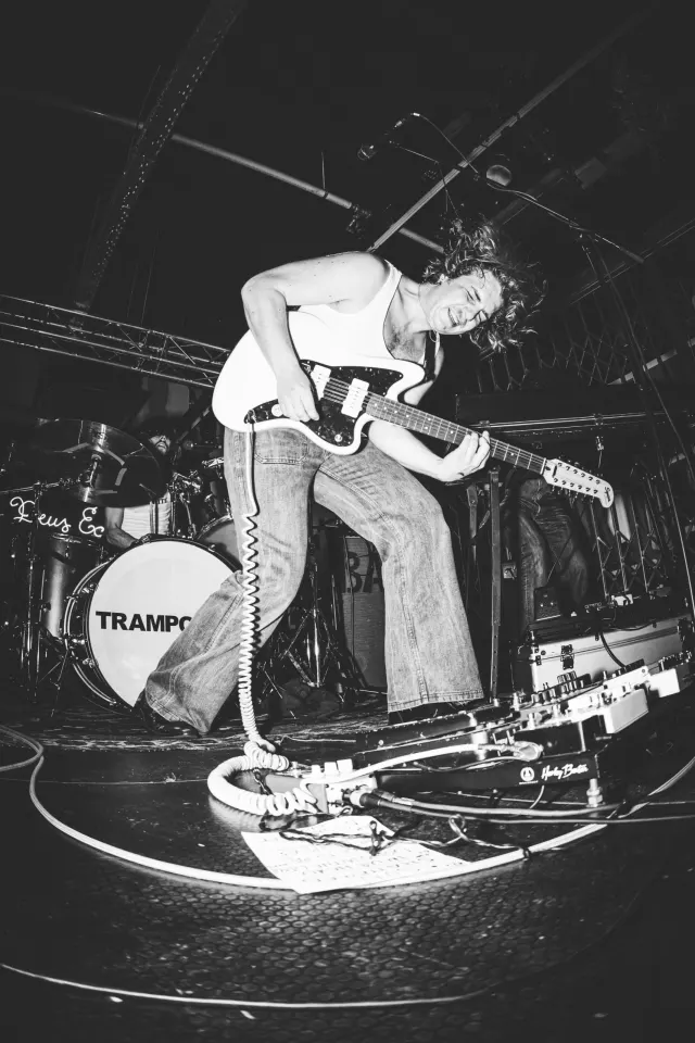 Guitariste en plein saut sur scène, photo noir et blanc